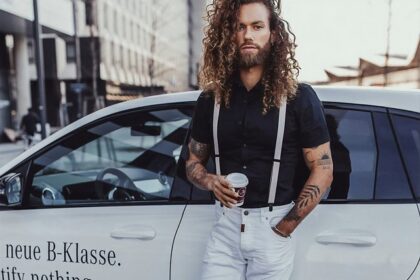 A man showcasing a stylish hairstyle for men with long curly hair, featuring well-defined, naturally flowing curls. His trendy, confident look highlights the versatility of curly hairstyles for men, perfect for both casual and formal settings